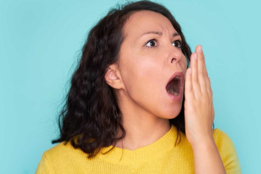 Bad Breath A woman checking her breath with a disgusted expression, illustrating the topic of bad breath prevention.